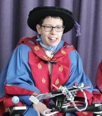 Beth Moulam Doctor or Health (hc) dressed in blue and red robes for the award ceremony at Manchester Metropolitan University